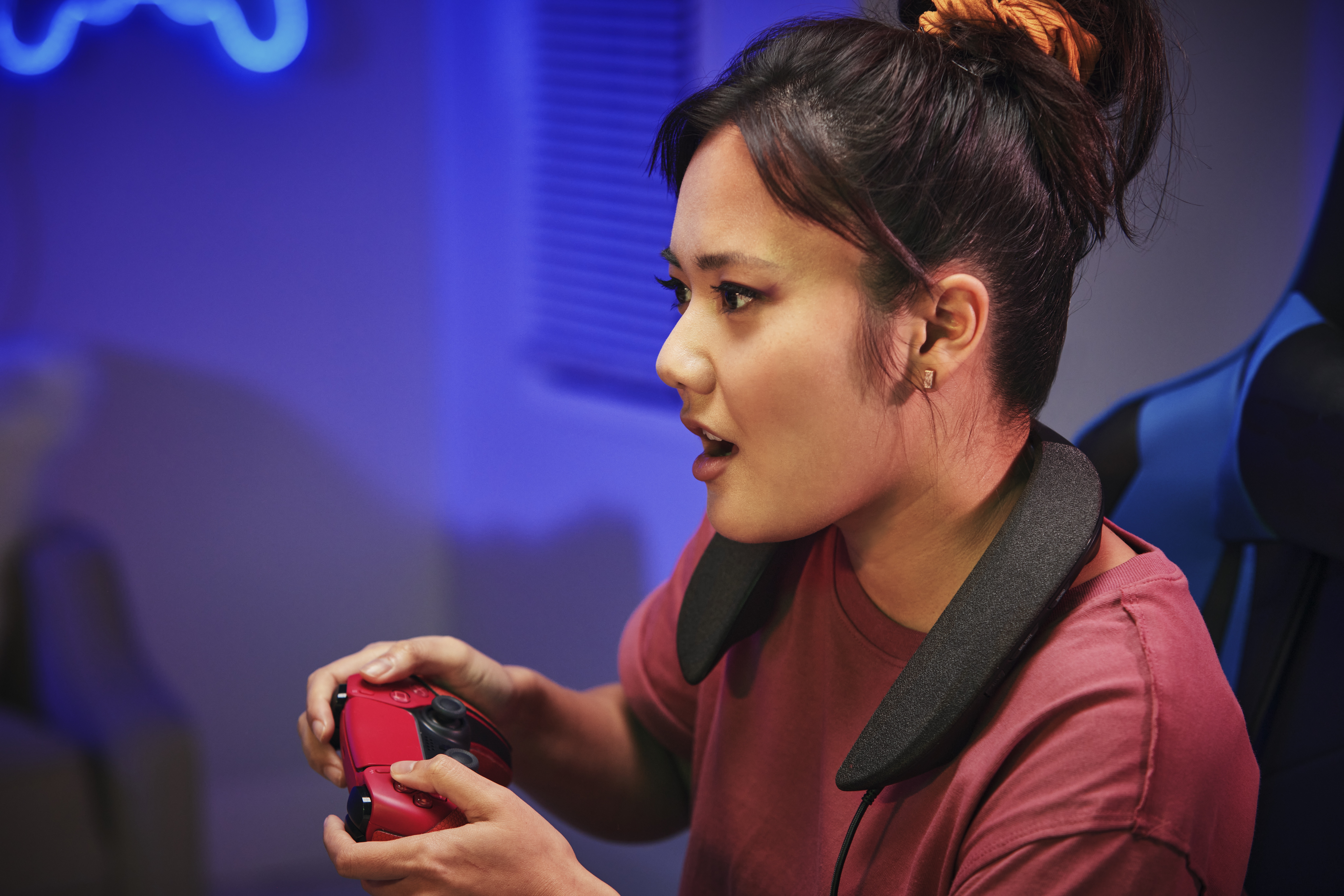 Una mujer disfruta jugando mientras usa el parlante portátil SoundSlayer de Panasonic.