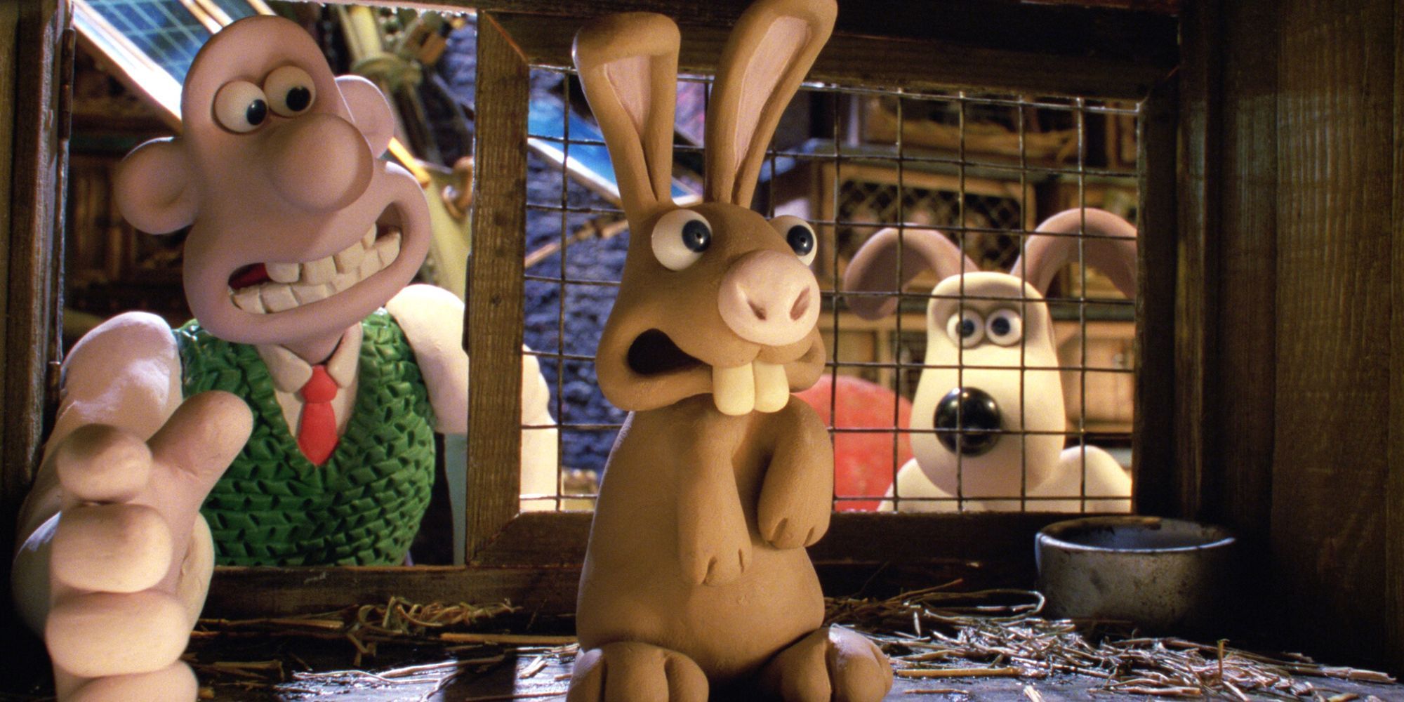 Wallace metiendo la mano en una jaula para sacar un conejo mientras Gromit está detrás de él en Wallace & Gromit: The Curse of the Were-Rabbit