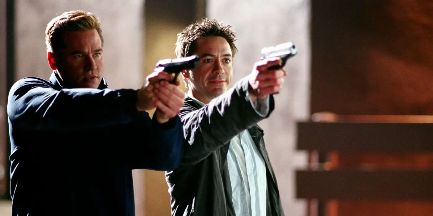 Val Kilmer y Robert Downey Jr. apuntando sus armas en la misma dirección en la película Kiss Kiss Bang Bang