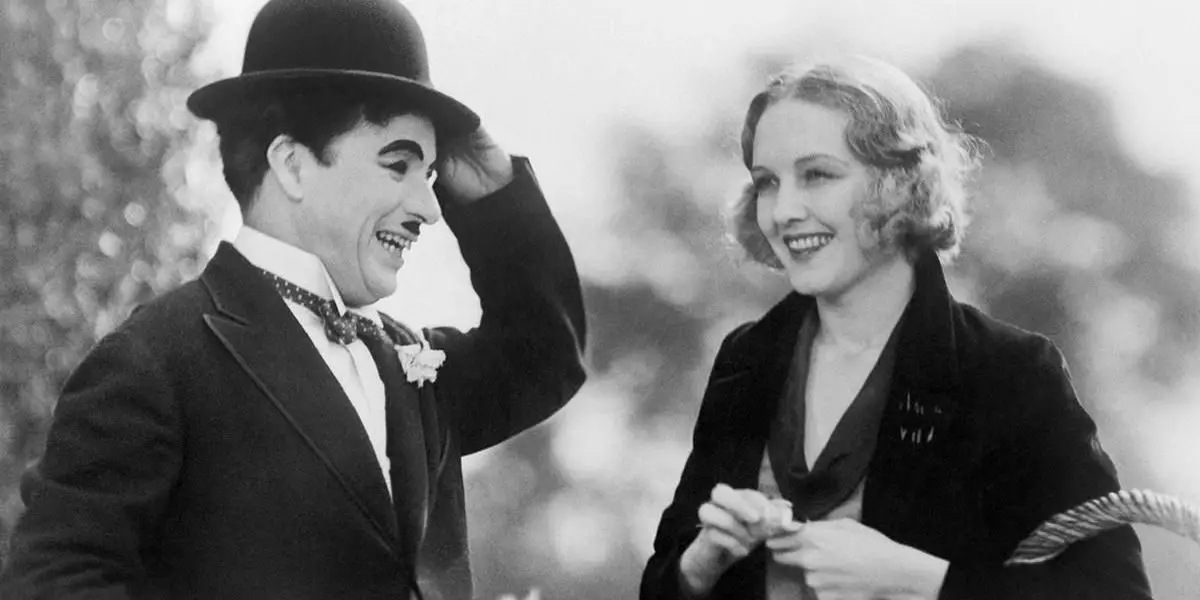 Charlie Chaplin y Virginia Cherrill como El vagabundo y la niña ciega sonriendo en Luces de la ciudad.