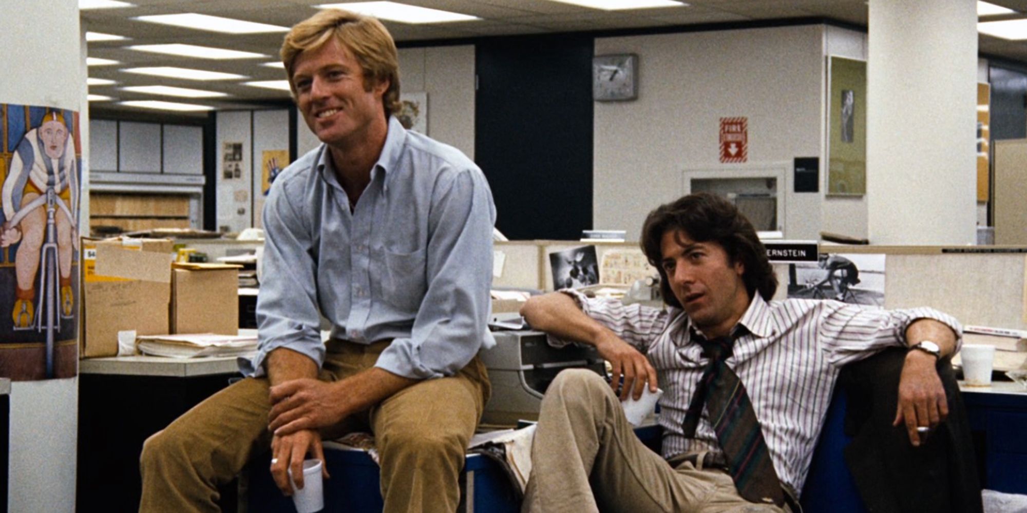 Robert Redford y Dustin Hoffman sentados en un escritorio en Todos los hombres del presidente