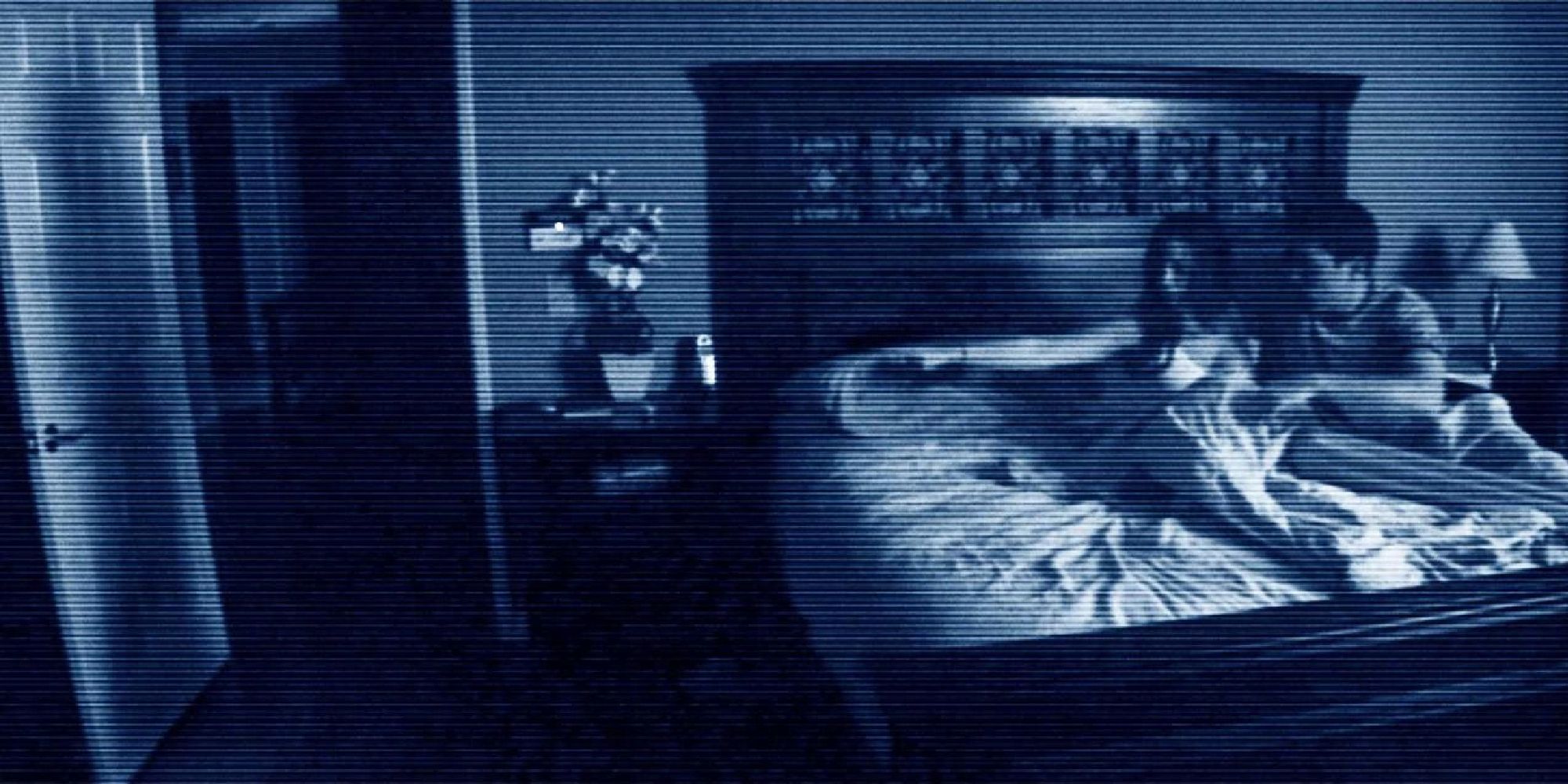 Imágenes de una mujer y su marido sentados en su cama mientras ella señala con el dedo la puerta en mitad de la noche en 'Actividad Paranormal'