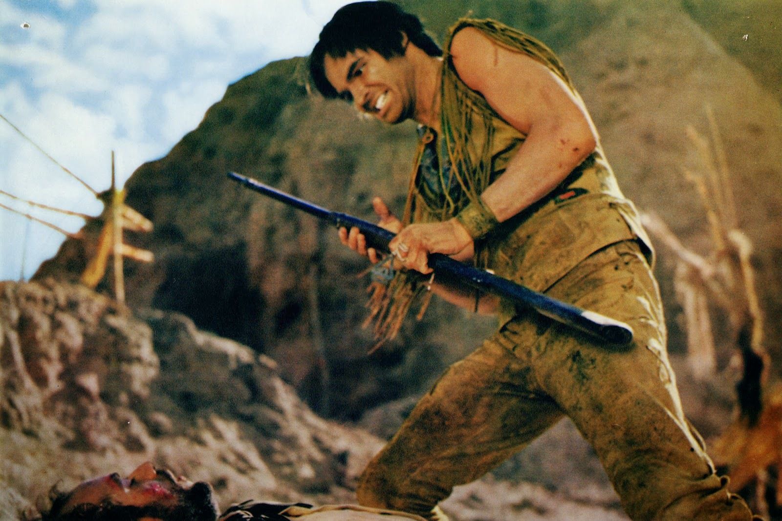 Burt Reynolds sin bigote está parado en una colina con ira en una escena de Navajo Joe