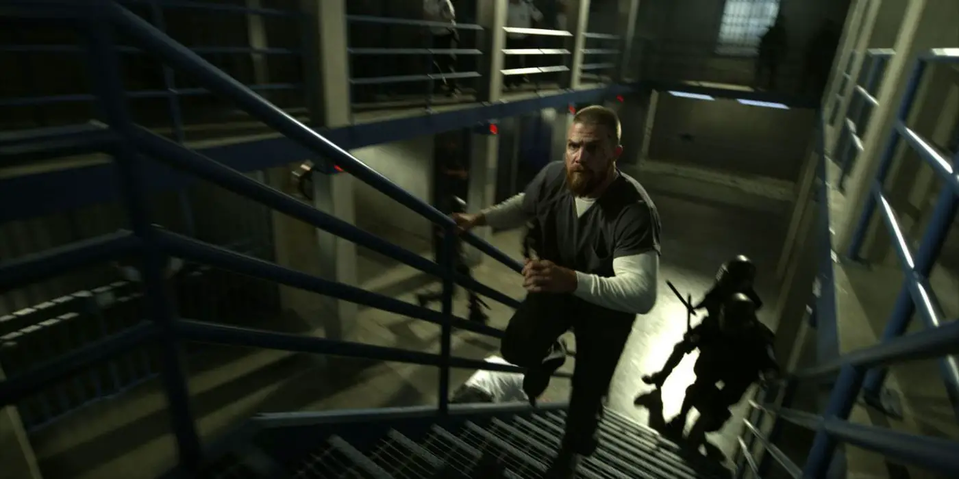 Oliver Queen huyendo de los guardias de la prisión en Arrow