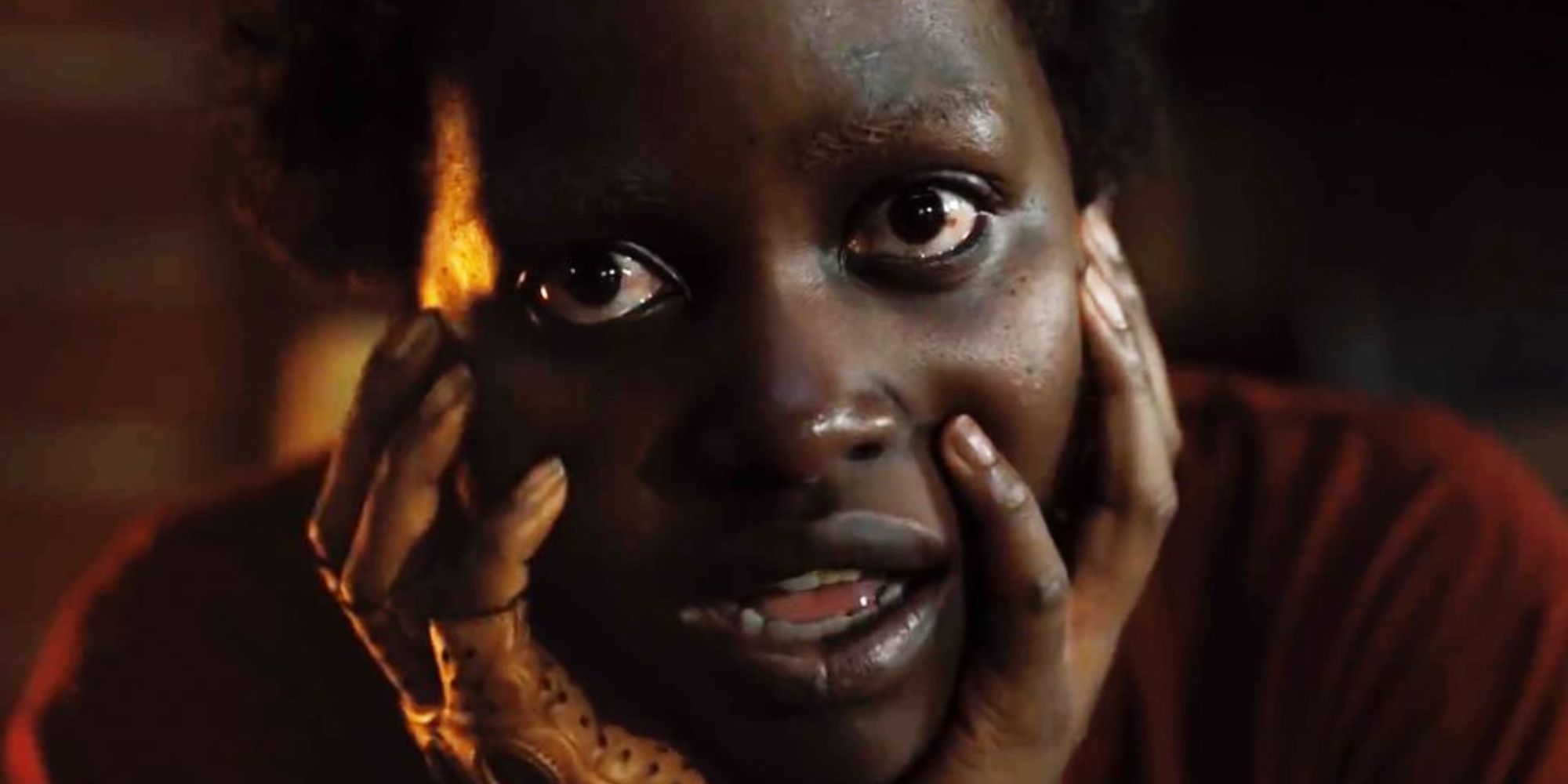 Primer plano de Lupita Nyong'o como Red mirando a la cámara con las manos en la cara en la película Nosotros 