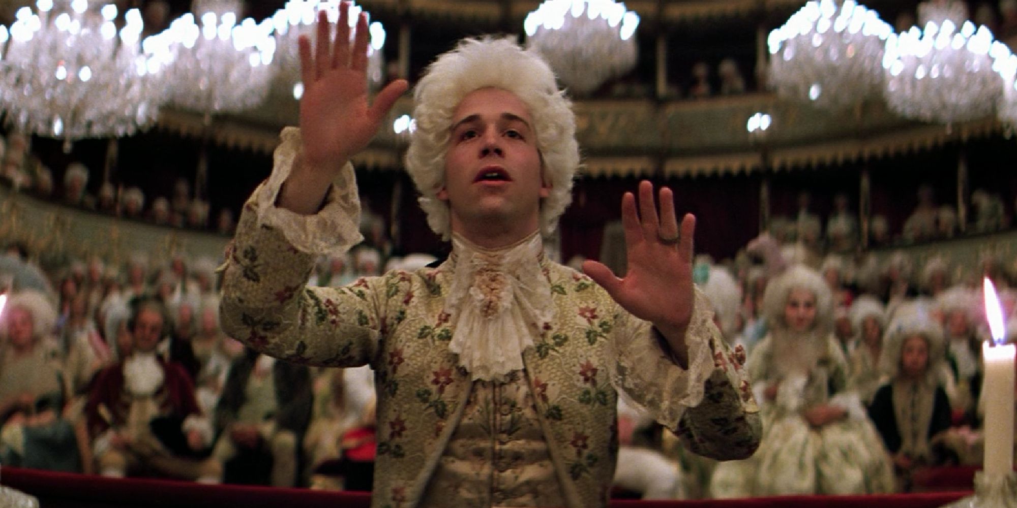 Tom Hulce como Mozart dirigiendo mientras el público se sienta detrás en Amadeus