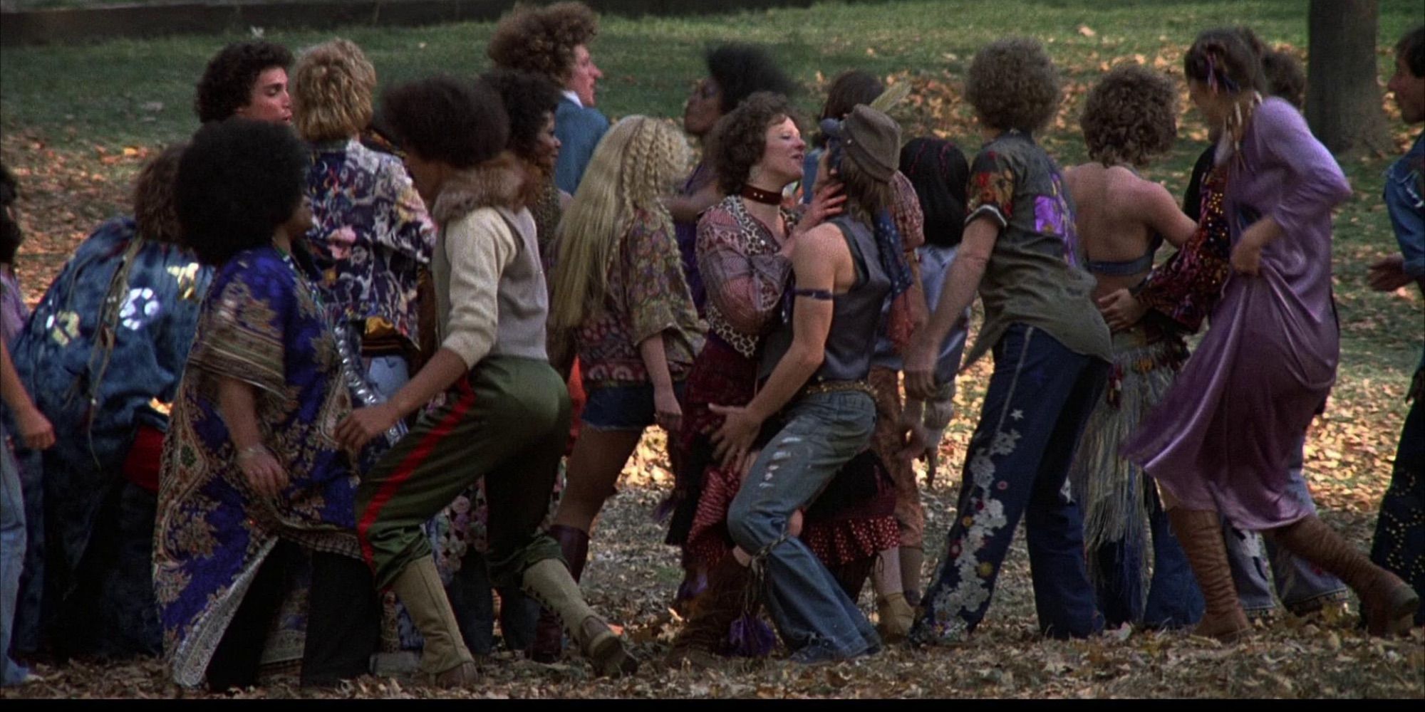Un grupo de personas bailando en un campo abierto en la película Hair.