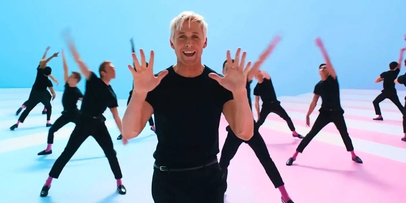 Una captura de pantalla de Barbie donde Ken de Ryan Gosling está de pie y sonriendo mientras levanta diez dedos.  El fondo es una pared azul y un suelo azul y rosa, y varios otros Kens, vestidos de negro como Gosling, bailan al fondo.