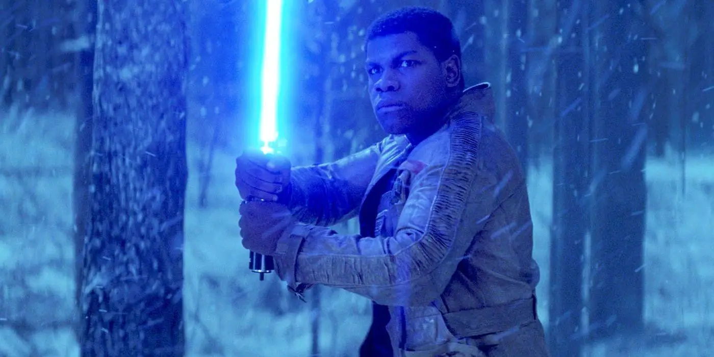 John Boyega como Finn empuñando un sable de luz azul en Star Wars The Force Awakens