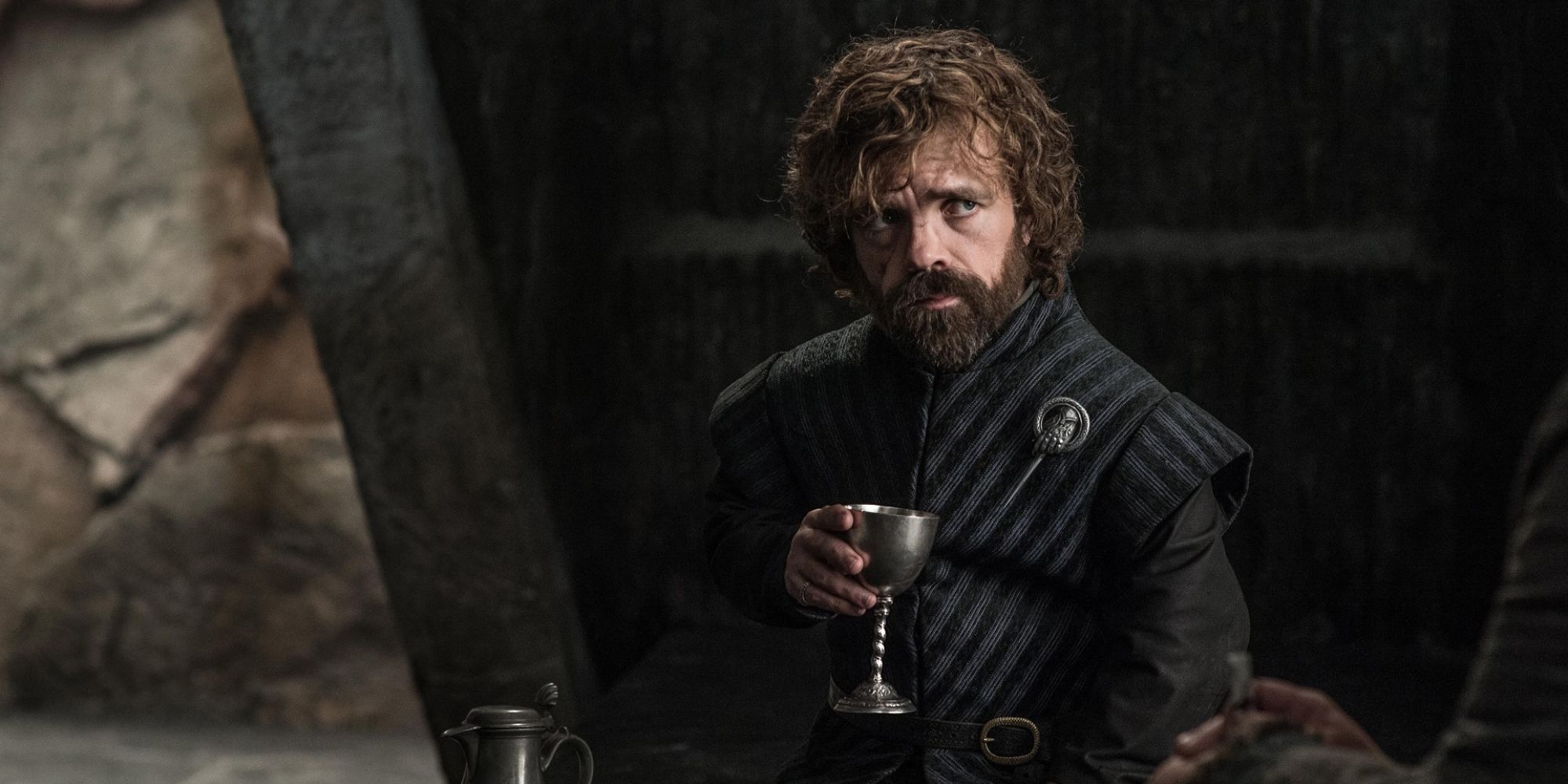 Peter Dinklage como Tyrion Lannister sentado y bebiendo de una copa en Juego de Tronos.