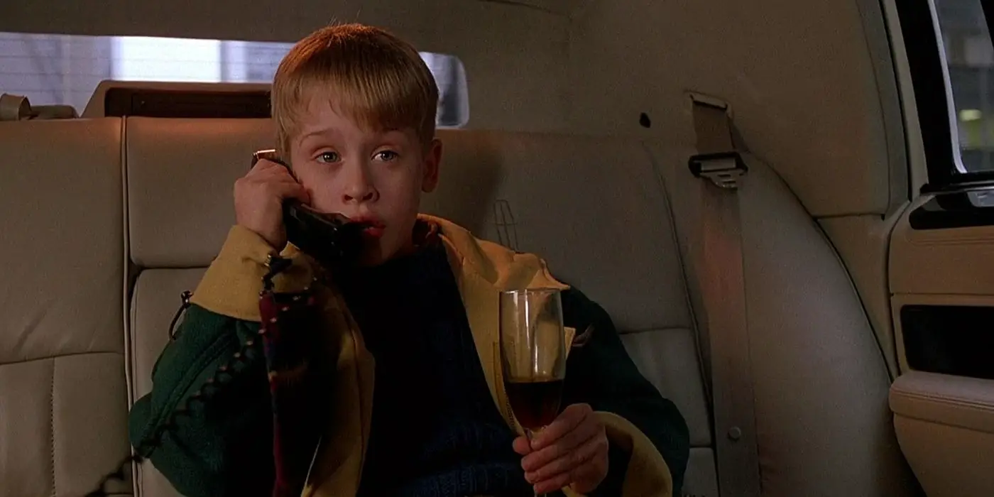 Kevin McCallister de Macaulay Culkin en la parte trasera de una limusina con un teléfono en una mano y un vaso en la otra en Solo en casa 2: Perdido en Nueva York