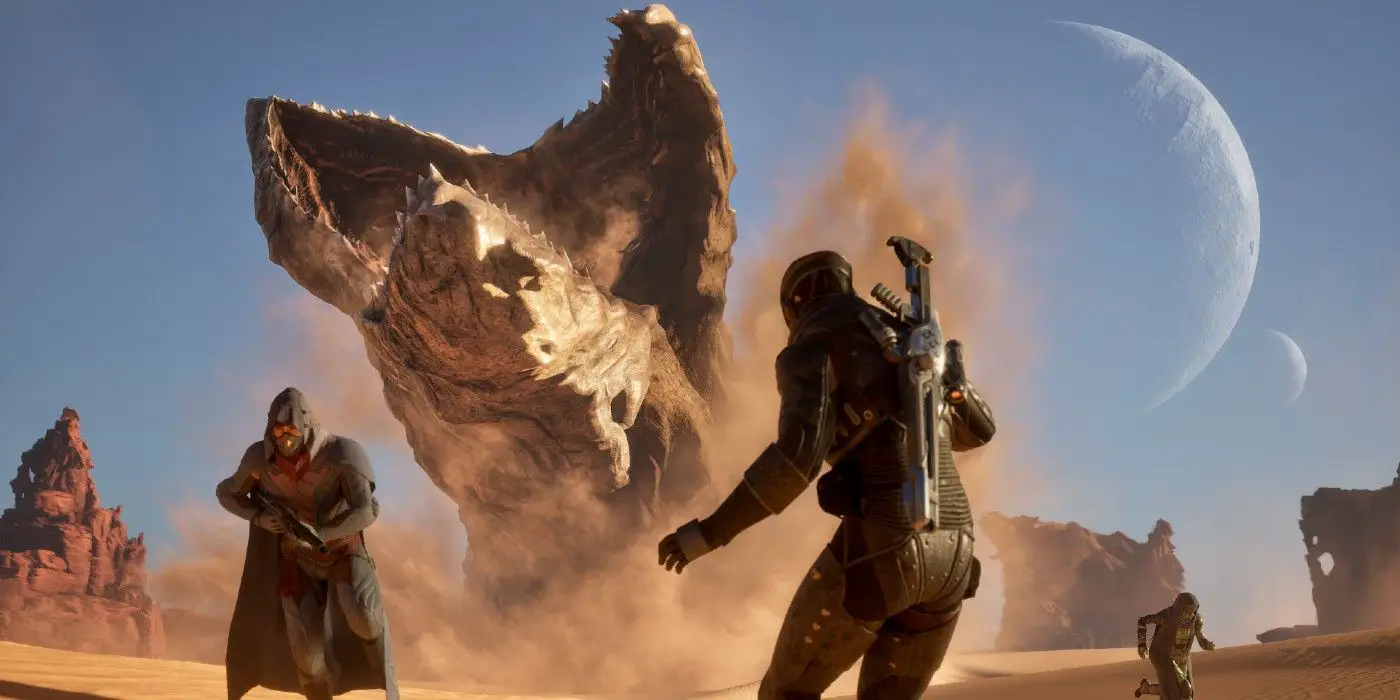 El gusano de arena gigante de Dune Awakening sale del suelo, dos personas están en el suelo, una volteada y otra mirando a la criatura.