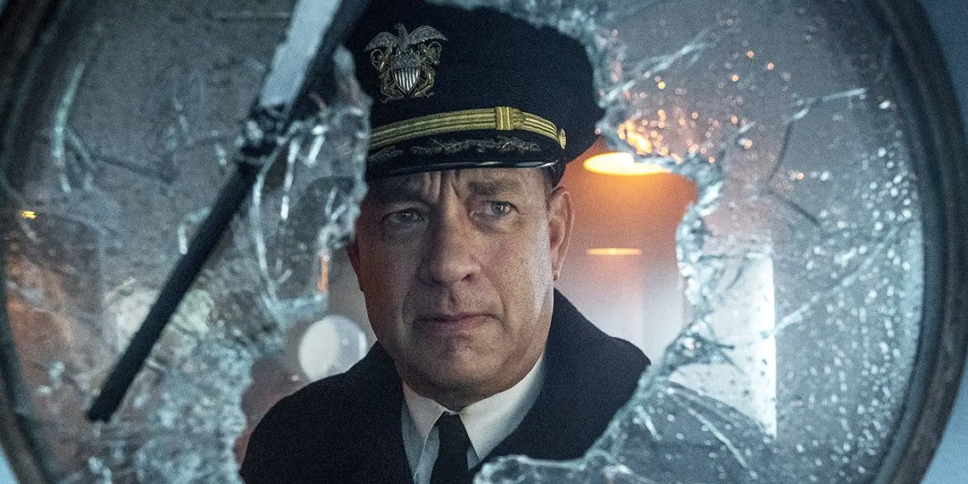 Tom Hanks como el comandante Ernie Krause mirando por una ventana rota en Greyhound.