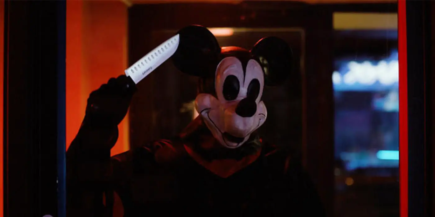 Simon Phillips-= como Mickey, sosteniendo un cuchillo.
