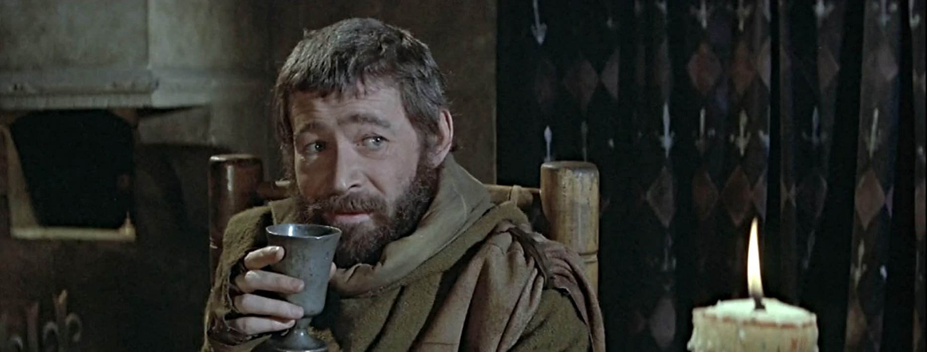 Peter O'Toole como Enrique II luciendo sarcástico y bebiendo en El león en invierno