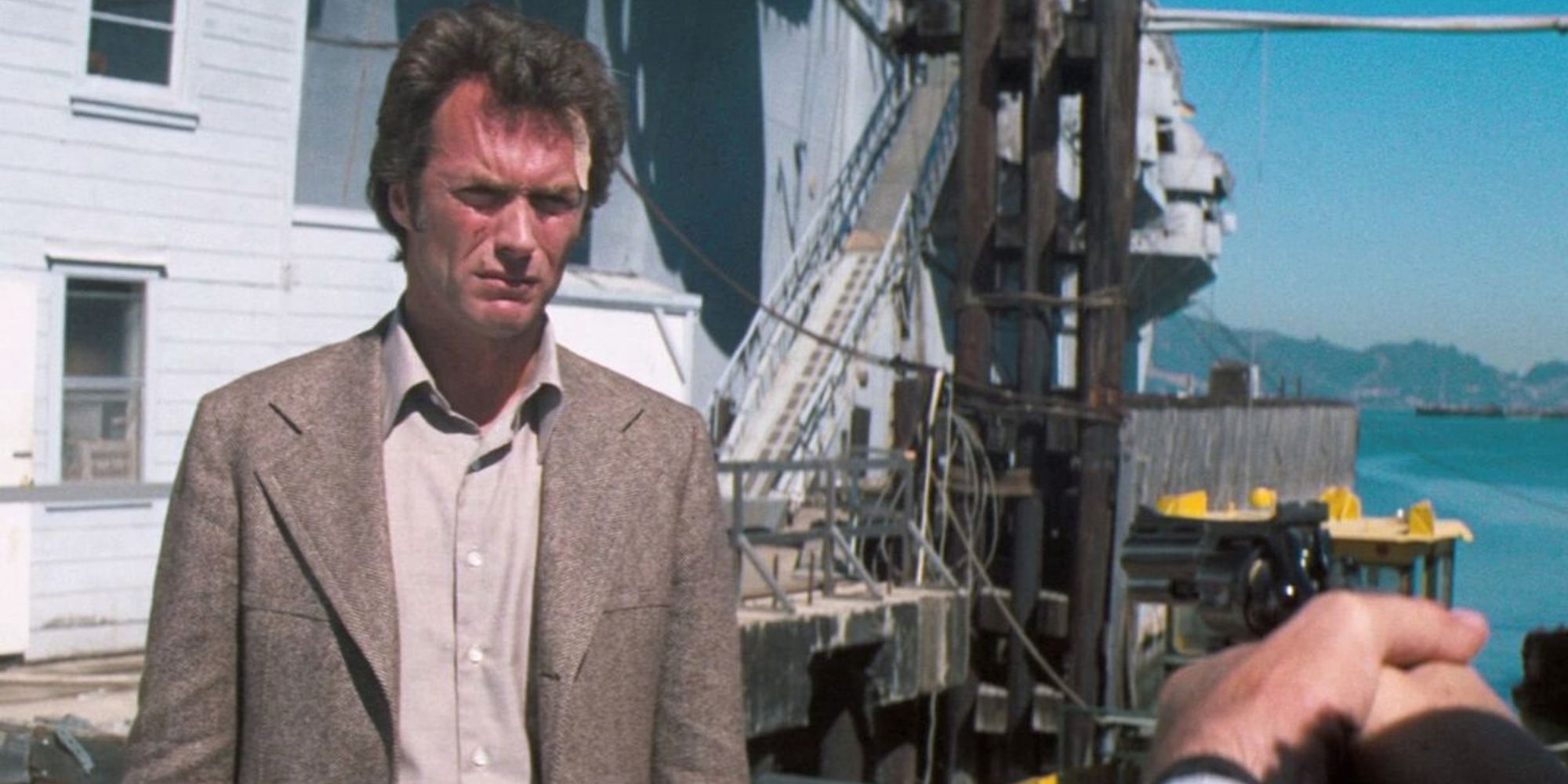 Clint Eastwood como Harry Callahan parado en un puerto deportivo mirando a alguien fuera de la pantalla en Magnum Force