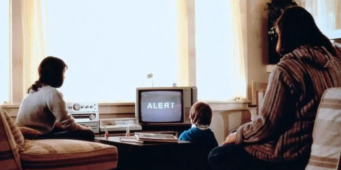 Una mujer y dos niños ven una alerta en la televisión mientras se ve una explosión nuclear desde las ventanas en 'Testamento'.