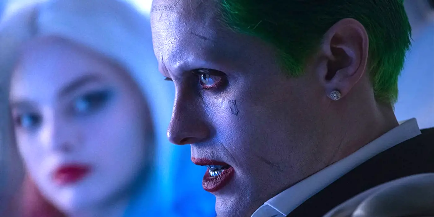 Jared Leto como el Joker, mirando hacia adelante mientras Harley Quinn (Margot Robbie) lo mira en Suicide Squad