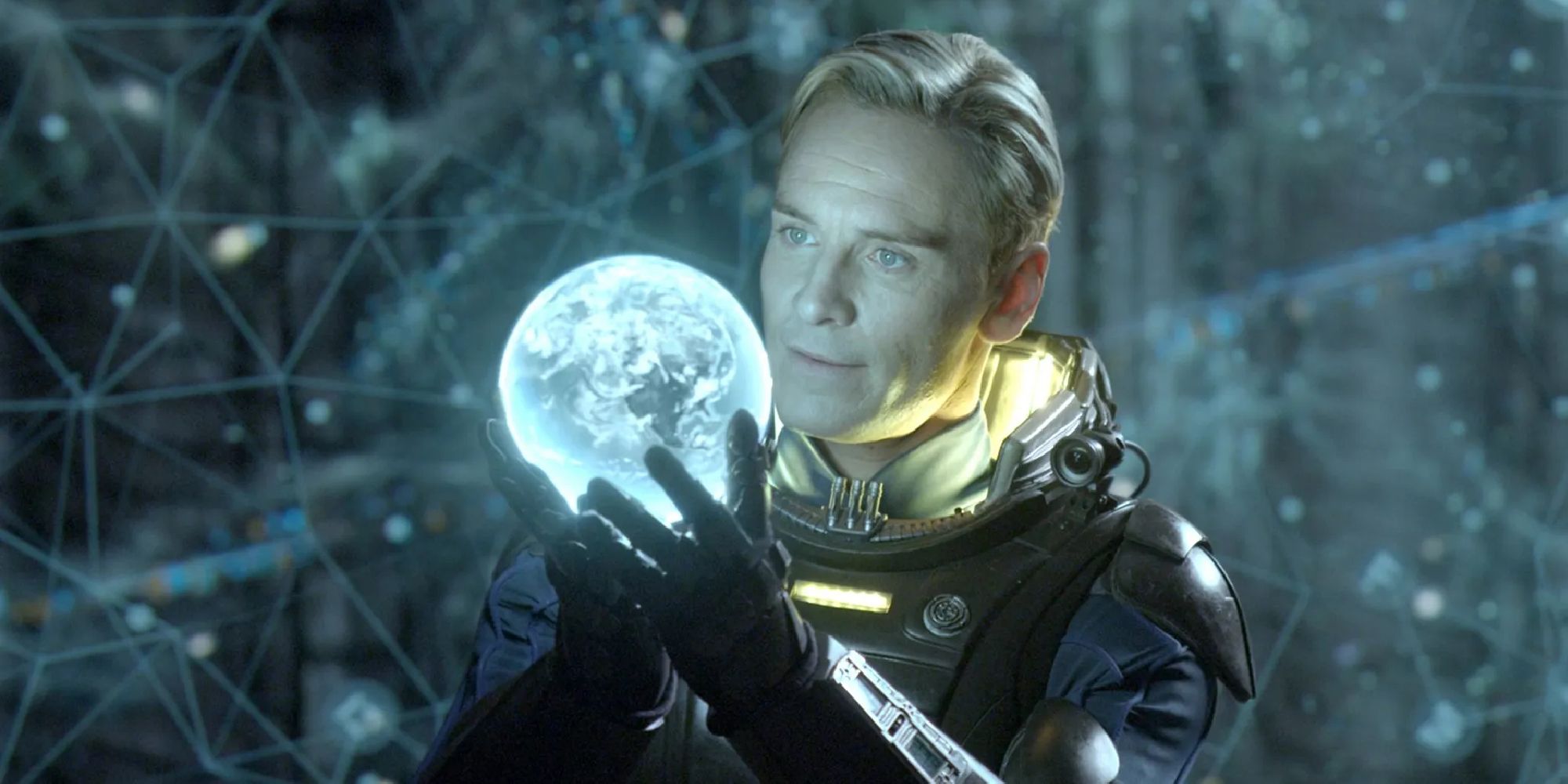 Michael Fassbender como David el androide examinando una esfera brillante en Prometheus.